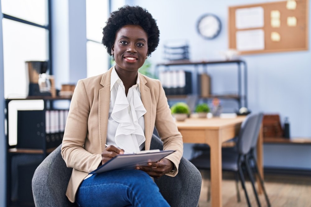 Young,African,American,Woman,Business,Worker,Writing,On,Paperwork,Sitting